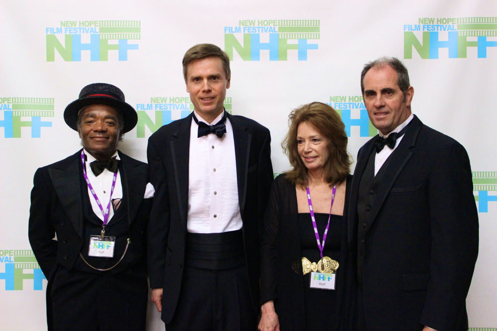 Four people wearing formal wear with a film festival wall banner in the background